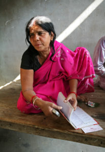 Photo of a Indian woman in a pink dress flipping through a book