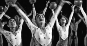 The scene shows women dancers holding balls in their hand. 