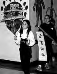 Students parade through the hallways of New Prospect Elementary School in Alpharetta, Georgia. One girl is holding a kite and other girl is holding a banner. On the banner writes four characters.