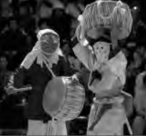 Two actors are playing traditional Korean performance. They wear masks and play drums. 