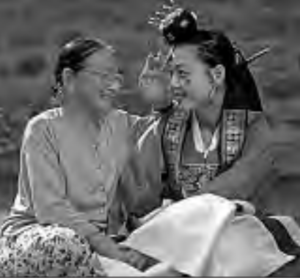 Two women in a play. One dresses as an ordinary modern woman. She is touching another woman who dresses a traditional Korean wearing. 