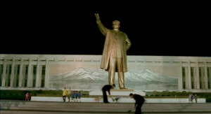 Mr. Hong sweeping the stairs in front of a statue of Kim Il Sung.