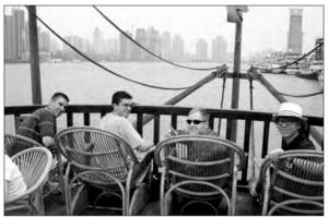 Photo of four men sitting on a boat smiling back