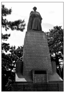 A statue of a man (Ryoma Sakamoto) stands on the top of a square stone.
