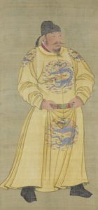 A depiction of Emperor Taizong, a middle-aged man with a long beard, wearing a yellow imperial robe adorned with a dragon pattern. He is also wearing a hat of the same design and has his hands placed on a red belt around his stomach. The painting captures the regal presence of Emperor Taizong, representing his imperial status and the grandeur of the era in which he ruled.