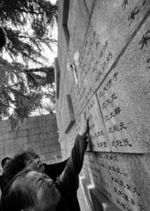 Two women with sad expressions touch the "atonement wall" of the Nanjing Massacre with their hands.