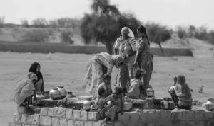 Women gather at a well with their children to draw water 