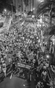 a photo of a protest where many hold a sign saying "we stand against china"