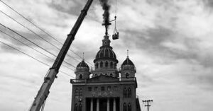 a photo of a church with a crane that leads to the top where a burning cross sits