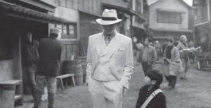 black and white photo of a man in a white suit and top hat speaking to a child
