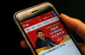 image of a hand holding a phone, the screen shows chinese text and an image of a man