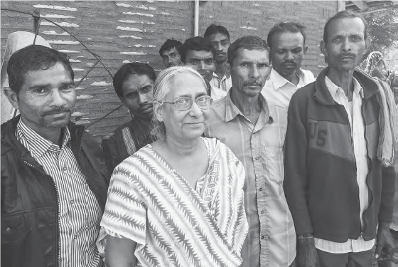 Photo of some Indian men and a woman posing outside the meeting hall at village.