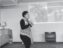 a woman stands in front of a screen speaking