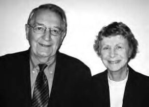 An elderly man and woman smile into the camera. 