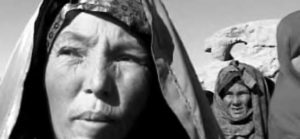 two women with head coverings squint in the sun