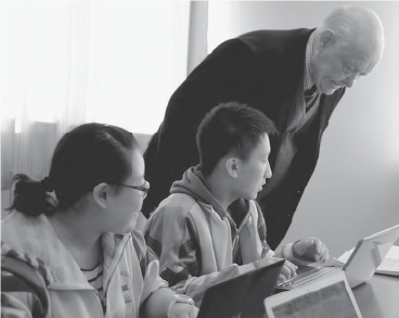 an old man looks over the shoulder of a young student