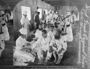photo of several wounded men in white gis being treated by nurses in white