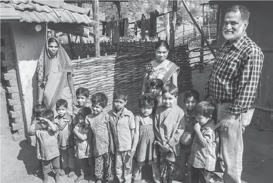 Image of a Western man posing with Indian children and two Indian women in the Indian village