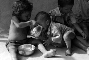 photo of a little boy giving his younger brother a drink