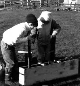 two children press dirt into a rectangular mold