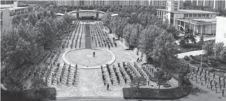 A campus courtyard filled with students arranged in lines, engaged in stretching exercises. The vibrant gathering showcases the students actively participating in physical wellness activities in an open and communal outdoor space.