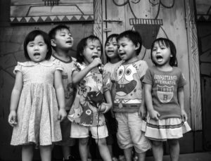 A group of six young children sing in front a a primary school in Taiwan. 