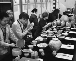 photo of several people examining various ceramics