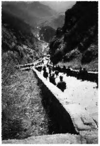 a view of a path that is long and winding, which leads up through a foggy mountain pass