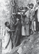 Image shows women and children hugging a tree