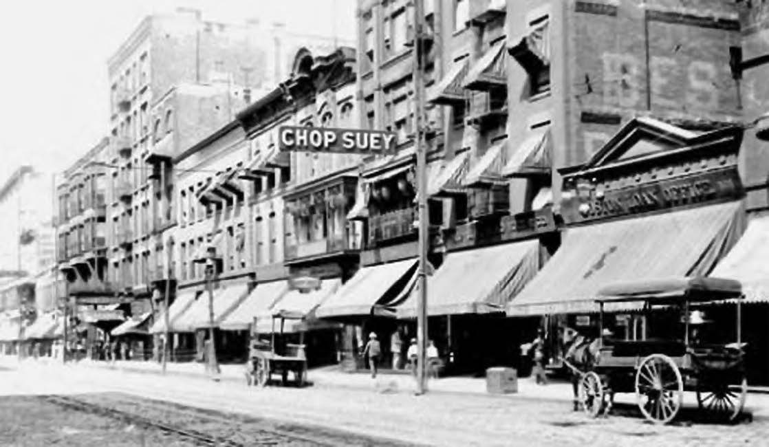 photo of a street with close together buildings with a sign for chop suey