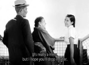 A young woman smiling and laughing with an older woman and man, with the screen caption "It's really a mess, but I hope you'll drop in later."