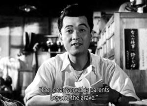 a man speaking, with the screen caption "None can serve his parents beyond the grave"