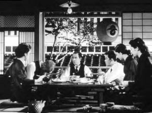 men and women sitting at a table in a japanese style room.