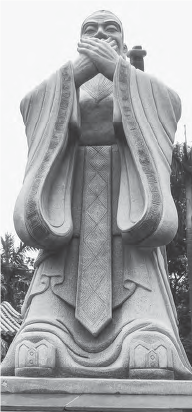 A large statue of Confucius, dressed in a Shenyi traditional robe, performing a traditional hand greeting gesture known as '抱拳.' The statue exudes a sense of reverence and cultural significance, representing the veneration of Confucius and the values associated with his teachings.