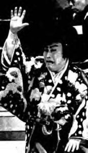 a person in kimono and white makeup raises their hand in drama