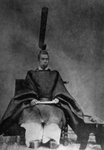 "Portrait of Emperor Mutsuhito of the Meiji era seated while wearing a sokutai, a traditional Japanese robe reserved for courtiers, aristocrats, and the emperor in the imperial court. The emperor is dressed in a simple traditional robe, reflecting the solemnity and formality of the occasion."