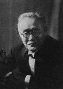 Photograph of Nitobe Inazō from the waist up. He is an elderly man wearing circular glasses and a Western style business suit. 