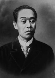 Photograph of Fukuzawa Yukichi from the waist up. He is a middle age man wearing a Western style business suit. He stares at the camera sternly.