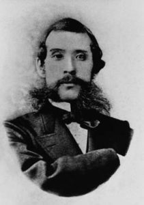 Portrait of Ōkubo Toshimichi's face. He is a middle-aged man with a long black beard. He is staring at the camera sternly and is wearing a Western style business suit.
