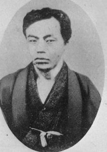 Photograph of Etō Shimpei as a young man from the waist up. He is wearing a traditional kimono and is staring intently at the photographer. 