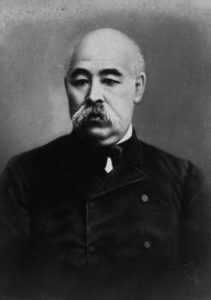 Photograph of Gotō Shōjirō from the waist up. He is a middle aged, bald man with a short graying mustache. He looks away from the camera and is wearing a black, simple waistcoat. 