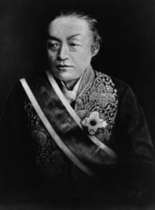 Waist up portrait of Iwakura Tomomi. He is a middle aged man and is wearing a traditional kimono with a military stash and badge. He looks away from the camera. 