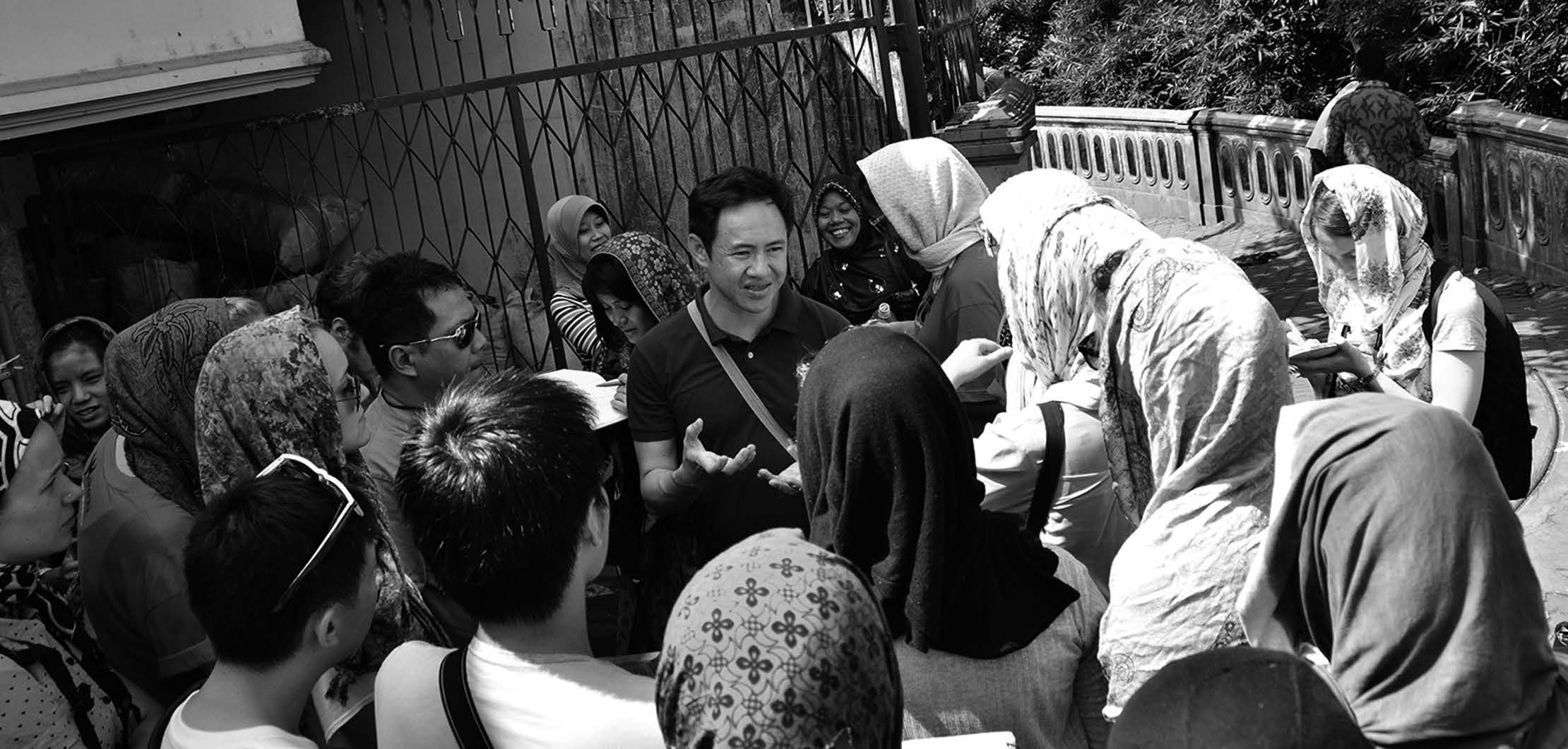 A group of students sit in a circle, listening intently to a teacher's presentation. 