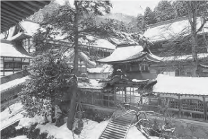 A serene winter scene featuring Eiheiji Temple and shrines covered in a blanket of snow. The snowy landscape adds a sense of tranquility and purity to the religious site, showcasing the harmonious integration of nature and spirituality.