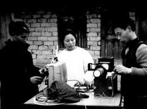 three people stand around film equipment