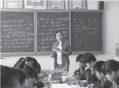 Wang Ping, an Asian woman, standing in front of a chalkboard and teaching her students. Engaged in the lesson, she imparts knowledge and interacts with the students, creating an engaging and educational classroom environment.