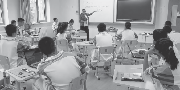 photo of a teacher teaching at the front of a classroom full of students in desks