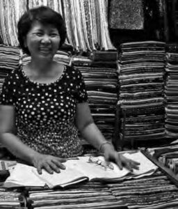 a woman smiles among stacks of fabric