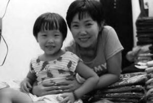 a woman and her young daughter smile among piles of folded jeans