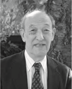 Photograph of Ezra Vogel. He is an elderly man smiling at the camera and wearing a business suit. 